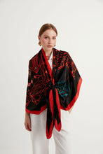 Load image into Gallery viewer, Discover the harmony of tradition and contemporary elegance with this timeless crepe silk shawl. This large shawl with mythological motifs, radiates warmth through red, black and white main colours, evoking a vibrant energy and life-giving power .
