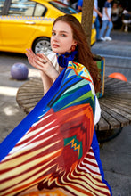 Load image into Gallery viewer, Discover the harmony of tradition and contemporary elegance with this timeless crepe silk shawl. This large shawl radiates warmth through its red, yellow and blue sunset colours, evoking a vibrant energy and life-giving power.
