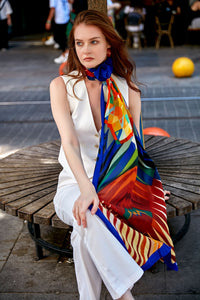 Discover the harmony of tradition and contemporary elegance with this timeless crepe silk shawl. This large shawl radiates warmth through its red, yellow and blue sunset colours, evoking a vibrant energy and life-giving power.