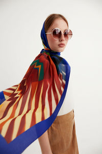 Discover the harmony of tradition and contemporary elegance with this timeless crepe silk shawl. This large shawl radiates warmth through its red, yellow and blue sunset colours, evoking a vibrant energy and life-giving power.